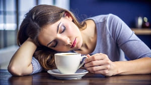 Уснувшая девушка с кружкой кофе